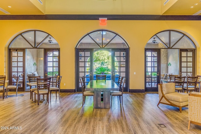 dining area featuring french doors, wood-type flooring, and a high ceiling