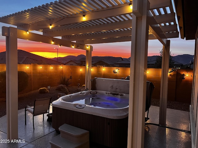 patio terrace at dusk featuring a hot tub and a pergola