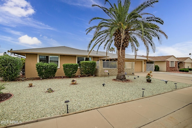 ranch-style house featuring a gate, concrete driveway, fence, a garage, and stucco siding