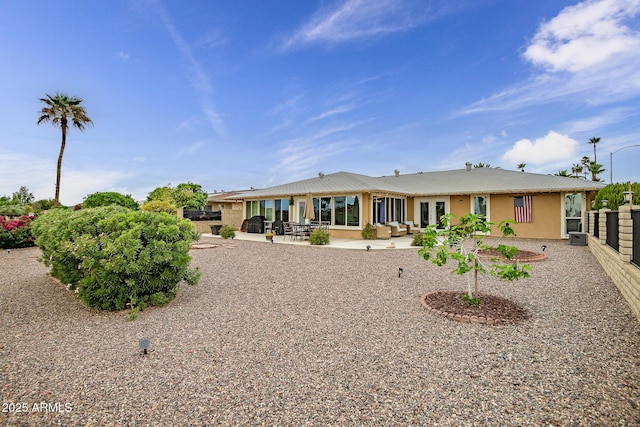 rear view of property featuring stucco siding, a patio area, and metal roof