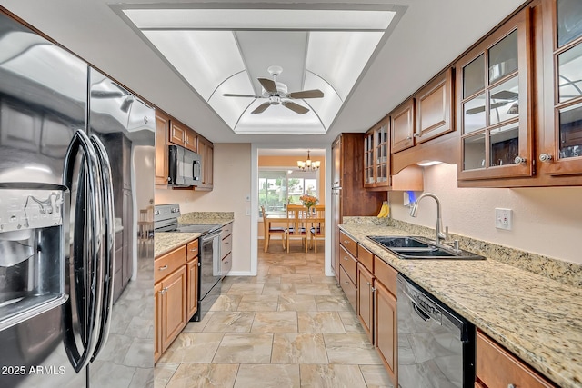 kitchen featuring light stone counters, brown cabinetry, a sink, and black appliances