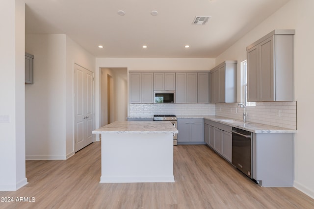 kitchen with sink, gray cabinets, stainless steel appliances, and a center island