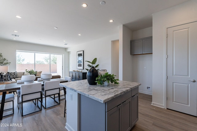 kitchen with sink, gray cabinetry, a center island, tasteful backsplash, and light hardwood / wood-style floors