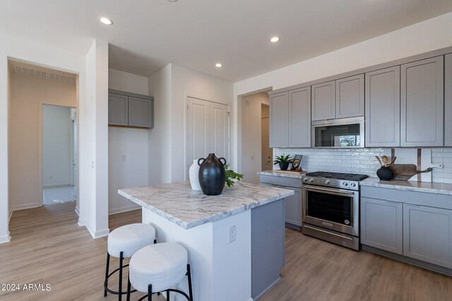 kitchen with light stone counters, light wood-type flooring, a kitchen island, and gray cabinetry