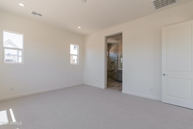 unfurnished bedroom with connected bathroom and light colored carpet