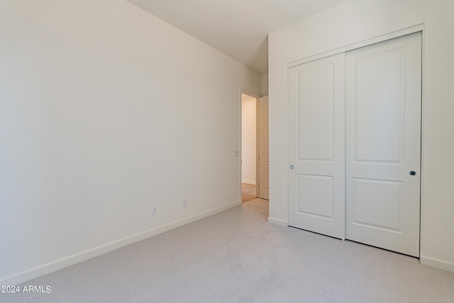 unfurnished bedroom with light carpet and a closet