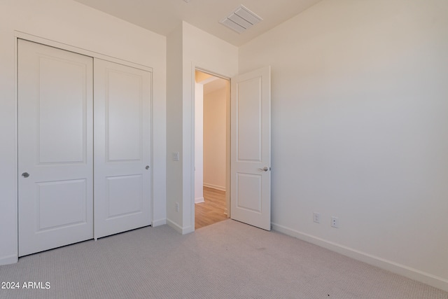 unfurnished bedroom featuring light carpet and a closet