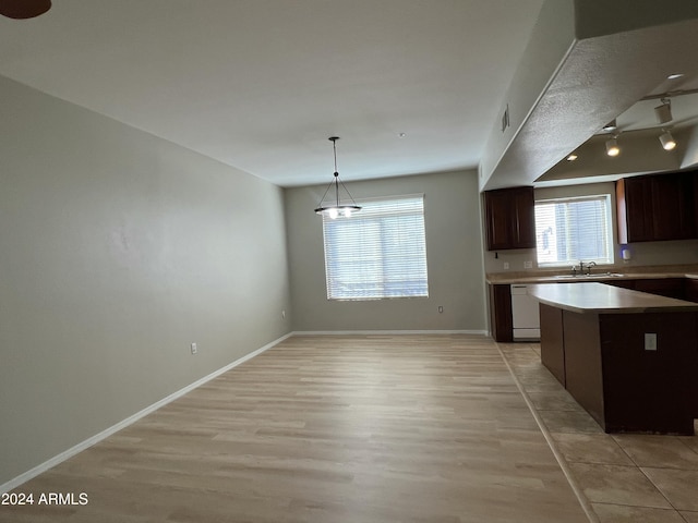 kitchen featuring dishwasher, a center island, sink, light hardwood / wood-style floors, and decorative light fixtures