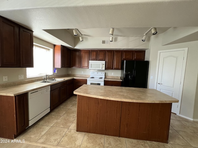 kitchen with a center island, rail lighting, sink, white appliances, and light tile patterned floors