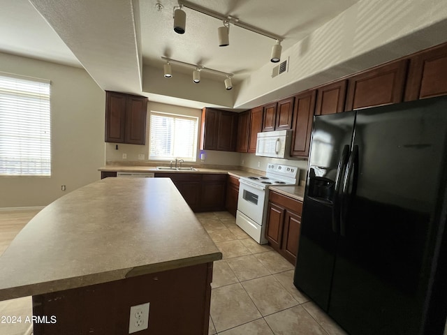 kitchen featuring track lighting, white appliances, sink, a kitchen island, and light tile patterned flooring