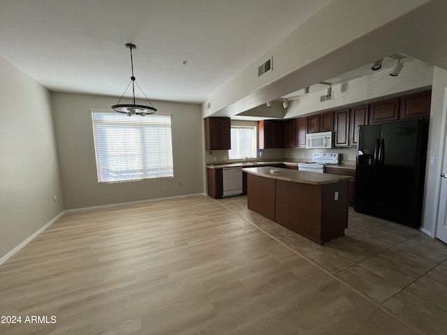 kitchen with a kitchen island, white appliances, hanging light fixtures, and light hardwood / wood-style flooring