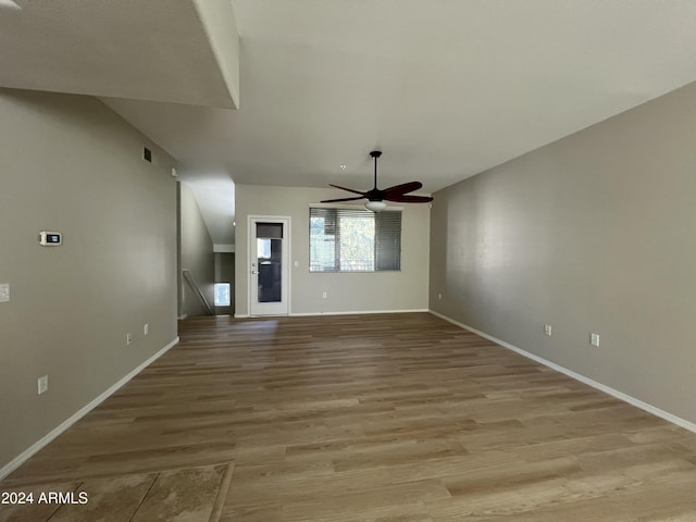 unfurnished living room featuring ceiling fan, light wood-type flooring, and vaulted ceiling