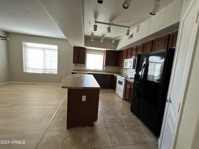 kitchen with a center island, white appliances, sink, light tile patterned flooring, and dark brown cabinetry