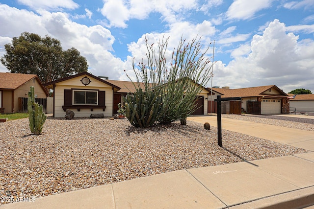 single story home featuring concrete driveway, a garage, and fence
