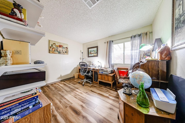 miscellaneous room with a textured ceiling, wood finished floors, and an office area