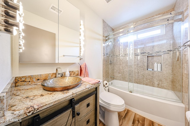 full bathroom featuring toilet, wood finished floors, vanity, and combined bath / shower with glass door