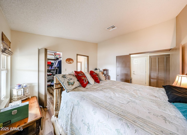 bedroom featuring a closet, wood finished floors, a textured ceiling, and a spacious closet