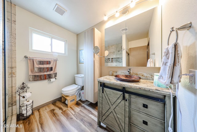 full bath featuring wood finished floors, vanity, toilet, a shower, and baseboards