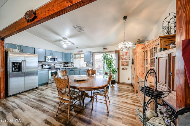 dining space featuring lofted ceiling, light wood-style flooring, a ceiling fan, and a chandelier