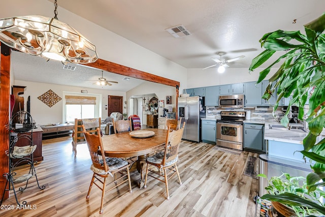dining area with a ceiling fan, light wood-style flooring, a chandelier, and a textured ceiling