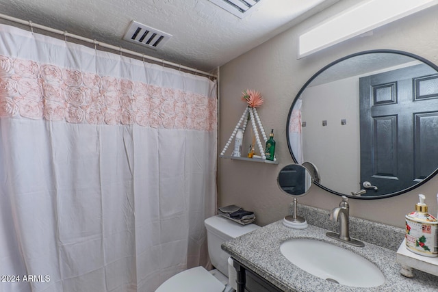 bathroom with vanity, toilet, and a textured ceiling