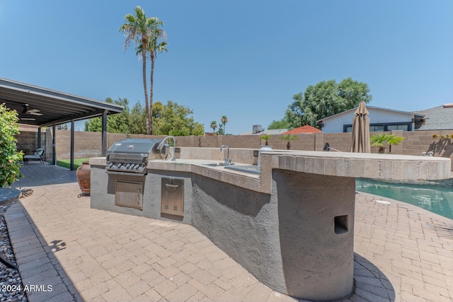 view of patio featuring sink, area for grilling, grilling area, ceiling fan, and a fenced in pool