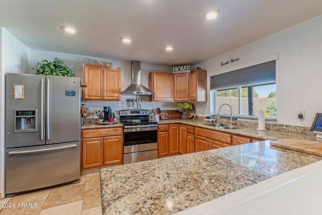 kitchen featuring light stone counters, wall chimney range hood, sink, and appliances with stainless steel finishes