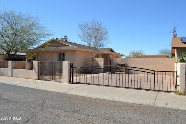 view of front facade with stucco siding, a fenced front yard, and a gate