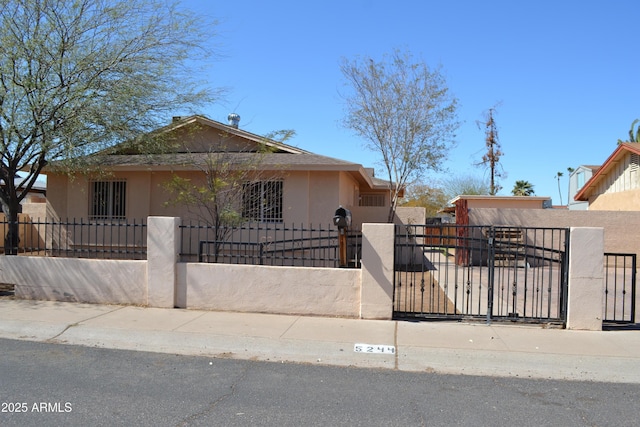 bungalow-style house featuring a gate, a fenced front yard, and stucco siding