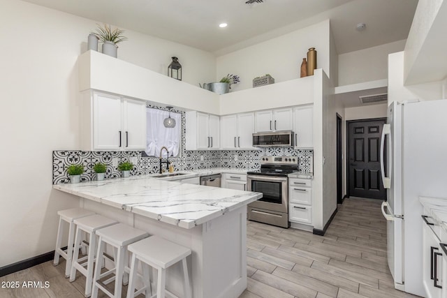 756 E Appaloosa Rd, Gilbert, AZ 85296 - kitchen featuring stainless steel appliances, a sink, a peninsula, tasteful backsplash, and light stone counters