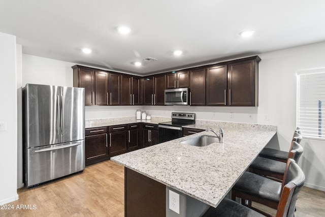 530 W Pintail Dr, Casa Grande, AZ 85122 - kitchen with appliances with stainless steel finishes, dark brown cabinets, a peninsula, light stone counters, and a breakfast bar area