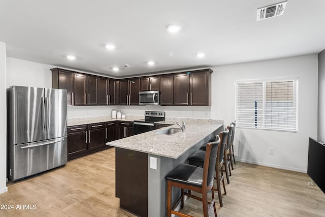 530 W Pintail Dr, Casa Grande, AZ 85122 - kitchen featuring stainless steel appliances, a peninsula, dark brown cabinetry, light wood-style flooring, and recessed lighting