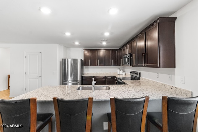 530 W Pintail Dr, Casa Grande, AZ 85122 - kitchen with stainless steel appliances, dark brown cabinets, light stone counters, recessed lighting, and a peninsula