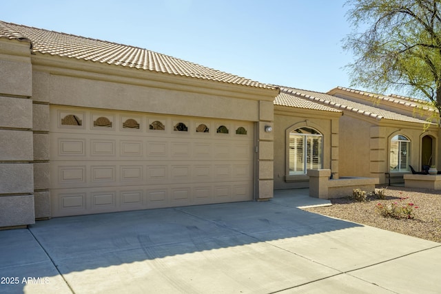 mediterranean / spanish-style home with driveway, an attached garage, a tiled roof, and stucco siding