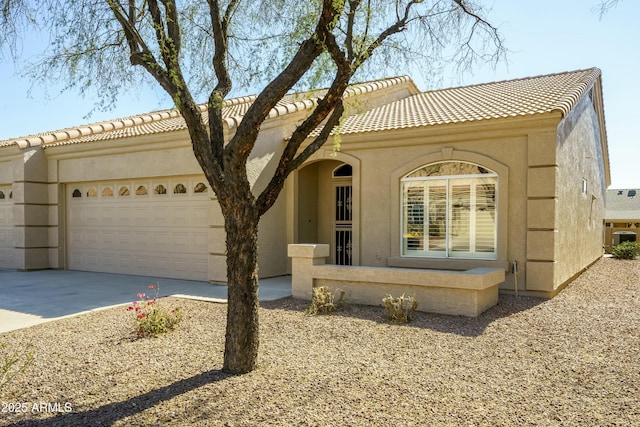 mediterranean / spanish-style home featuring driveway, a tiled roof, a garage, and stucco siding