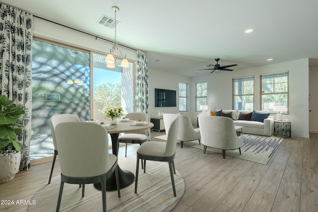 dining space featuring ceiling fan with notable chandelier and light hardwood / wood-style floors