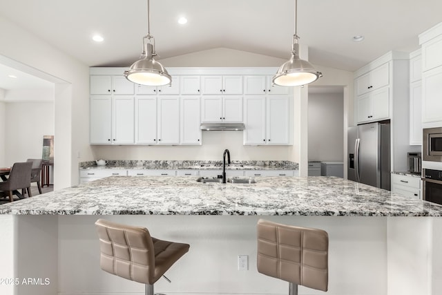 kitchen with stainless steel appliances, decorative light fixtures, and an island with sink