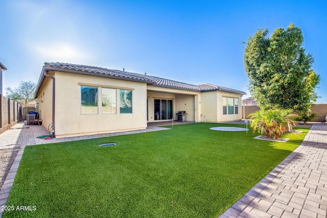 back of property with central air condition unit, a patio area, and a yard