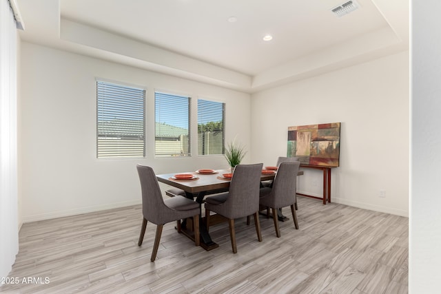 dining space featuring light hardwood / wood-style flooring and a raised ceiling