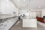 kitchen featuring white cabinetry, pendant lighting, and an island with sink