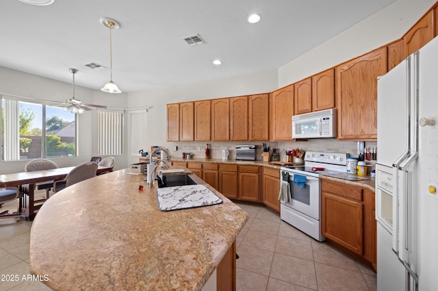 kitchen with a sink, backsplash, white appliances, and visible vents