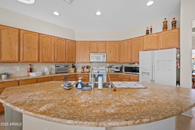 kitchen with white appliances, backsplash, recessed lighting, and a center island with sink