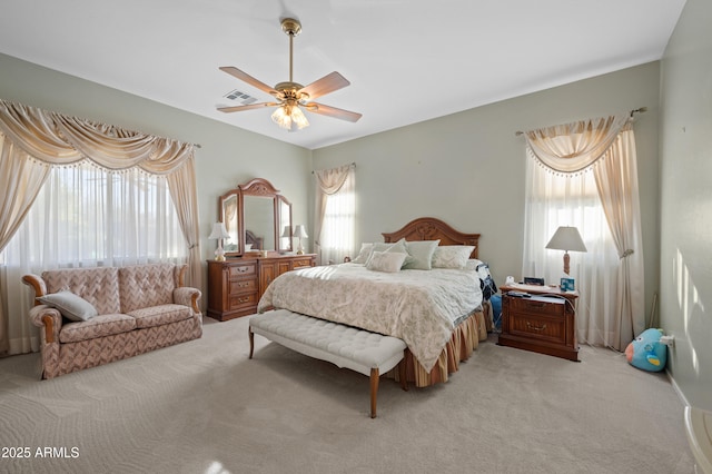 bedroom featuring ceiling fan, visible vents, multiple windows, and light carpet