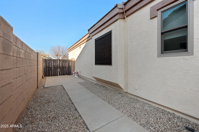 view of side of home with fence and stucco siding