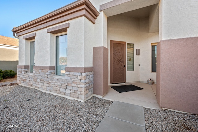 property entrance with stucco siding and stone siding