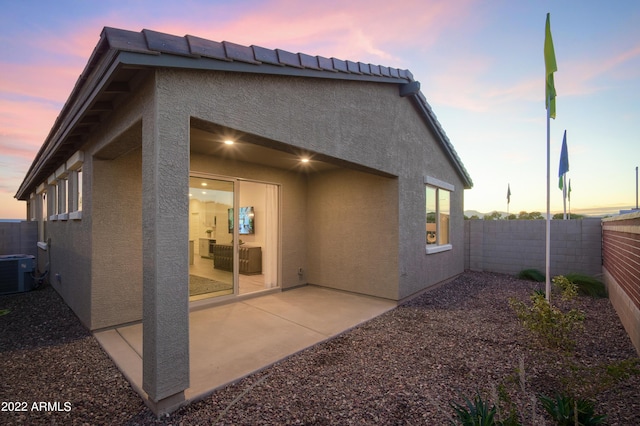 back house at dusk featuring a patio and central AC unit