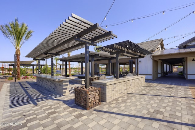 view of property's community with exterior kitchen, a pergola, an outdoor bar, and a patio