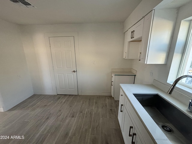 kitchen featuring white cabinets, light wood-type flooring, and sink