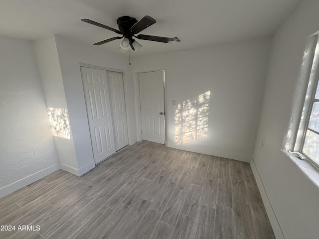 unfurnished bedroom featuring ceiling fan, a closet, and light hardwood / wood-style flooring