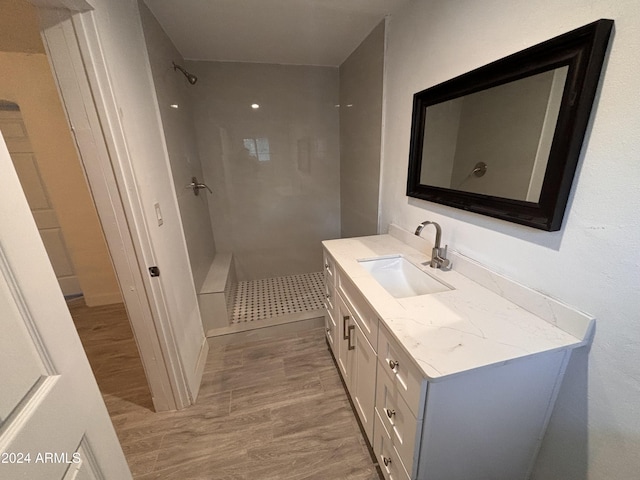 bathroom featuring a tile shower, vanity, and hardwood / wood-style floors